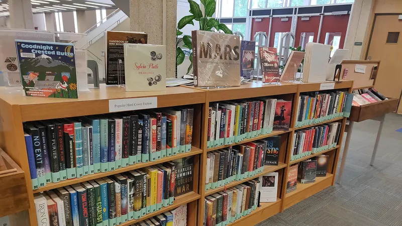 Rayonnages de livres dans une bibliothèque universitaire, avec des ouvrages présentés en vitrine